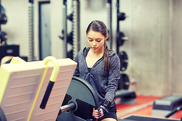 Image showing young woman adjusting leg press machine in gym