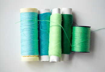 Image showing green and blue thread spools on table