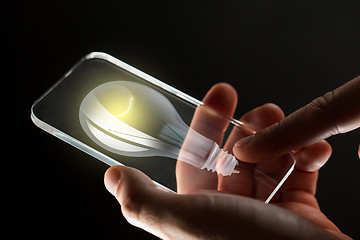 Image showing close up of hands with lightbulb smartphone