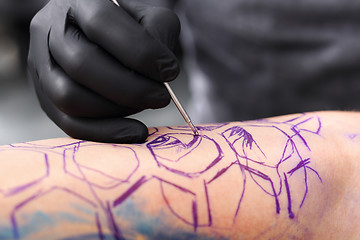 Image showing Tatoo drawing on his shoulder. Tattoo, tattoo artist does the tattoo on the man's hand.