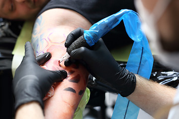 Image showing Colored tattoo on his hand. Making tattoo. Tattoo machine.