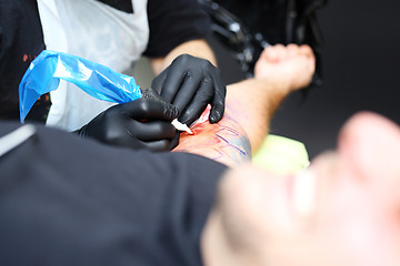 Image showing Tattooer tattooing color tattoo on his hand man