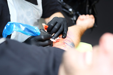 Image showing Colored tattoo on his hand. Making tattoo. Tattoo machine.