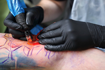 Image showing Tattooer tattooing color tattoo on his hand man