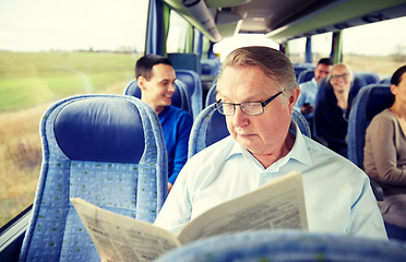 Image showing happy senior man reading newspaper in travel bus