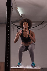 Image showing black female athlete is performing box jumps at gym