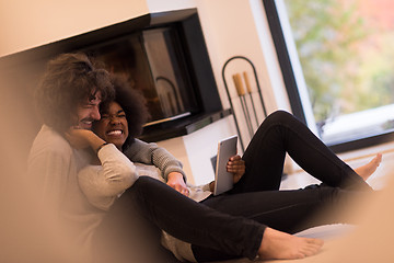 Image showing multiethnic couple using tablet computer on the floor