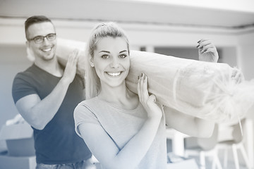 Image showing couple carrying a carpet moving in to new home