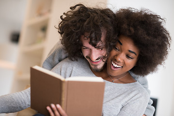 Image showing multiethnic couple hugging in front of fireplace