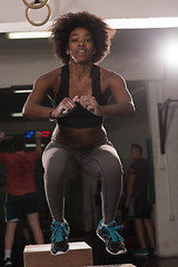 Image showing black female athlete is performing box jumps at gym