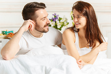 Image showing Young adult heterosexual couple lying on bed in bedroom