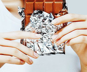 Image showing woman eating chocolate, close up hands with manicure french nails holding candy, beautiful fingers, lifestyle concept