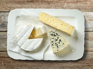 Image showing plate of various cheese on wooden table