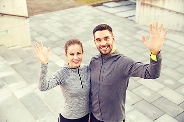 Image showing happy couple waving hands outdoors on city street