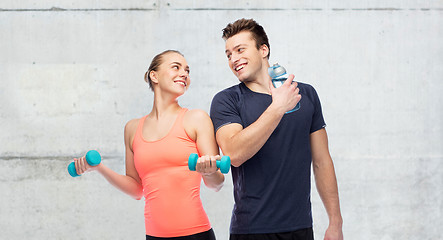 Image showing sportive man and woman with dumbbell and water