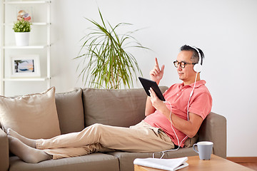 Image showing man with tablet pc and headphones at home