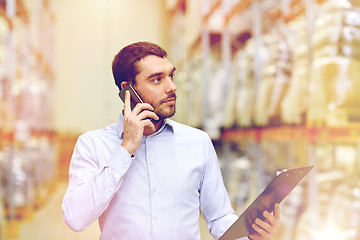 Image showing man with clipboard and smartphone at warehouse