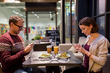 Image showing happy couple with smartphones at vegan restaurant