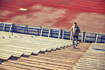 Image showing happy young man running upstairs on stadium