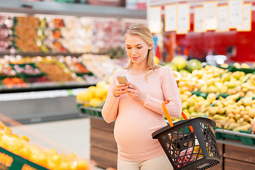 Image showing pregnant woman with shopping basket and smartphone