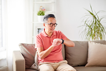 Image showing asian man checking time on wristwatch at home