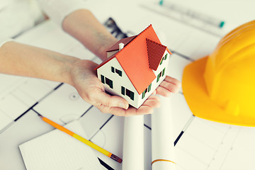 Image showing close up of hands with house model above blueprint