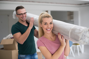 Image showing couple carrying a carpet moving in to new home
