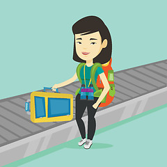 Image showing Woman picking up suitcase on luggage conveyor belt