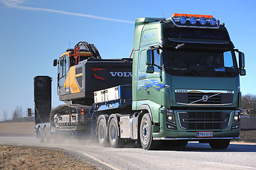 Image showing Volvo FH16 Hauls Construction Equipment Along Highway