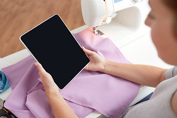 Image showing tailor with sewing machine, tablet pc and fabric