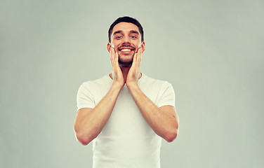 Image showing happy young man applying aftershave to face