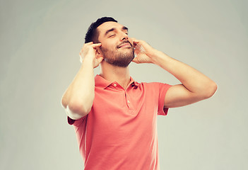 Image showing happy man listening to music over gray background
