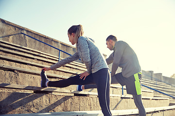 Image showing couple stretching leg on stands of stadium