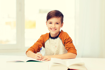 Image showing smiling student boy writing to notebook at home