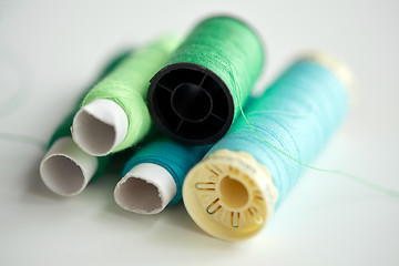 Image showing green and blue thread spools on table