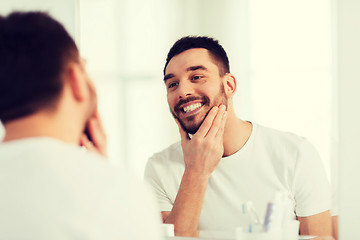 Image showing happy young man looking to mirror at home bathroom