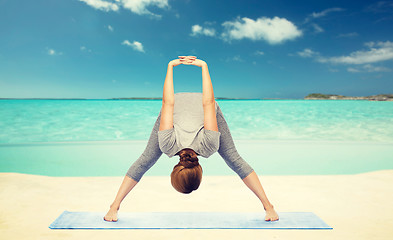 Image showing woman making yoga  forward bend on beach 