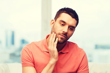 Image showing unhappy man suffering toothache at home