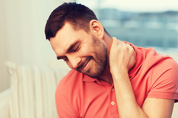 Image showing unhappy man suffering from neck pain at home