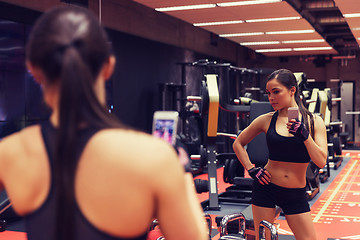 Image showing woman with smartphone taking mirror selfie in gym