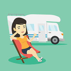 Image showing Woman sitting in chair in front of camper van.