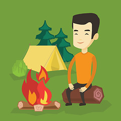 Image showing Man sitting on log near campfire in the camping.