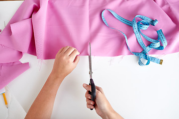 Image showing woman with tailor scissors cutting out fabric