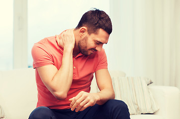 Image showing unhappy man suffering from neck pain at home