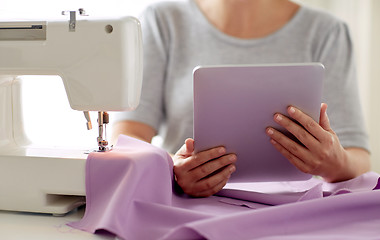 Image showing tailor with sewing machine, tablet pc and fabric