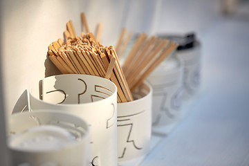 Image showing wooden drink stirrers in holder on table