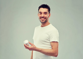 Image showing happy young man with cream jar over gray