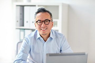 Image showing happy businessman in eyeglasses with laptop office