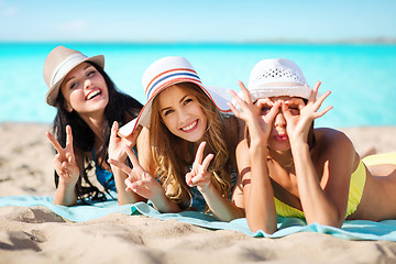 Image showing group of happy women in hats sunbathing on beach