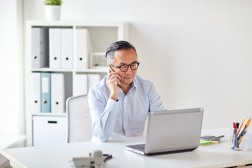 Image showing businessman with laptop calling on smartphone